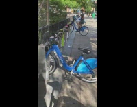 Lady pedals backwards locked blue rental bicycle 