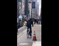 Guy balancing bottle on head rides bicycle 