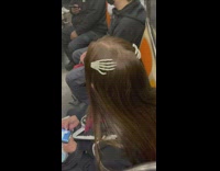 Woman with skeleton hand hairclip sit subway