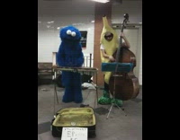 Cookie monster plays xylophone and guy in banana suit costume plays cello