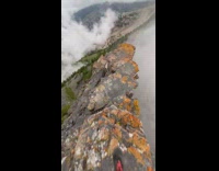 Man runs on the cliff edge of the rocky mountain