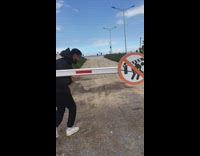 Guy walks under gate arm with sign that says not to go under