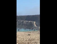 Guys with blue smoke bomb beach hill