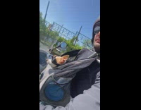 Man riding motorcycle with woman and dog goggles 