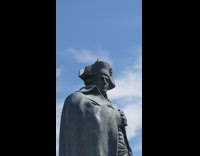 Wild bird tweets while on top of the hat of the statue