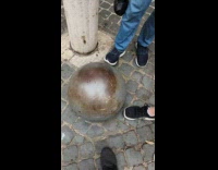 Three people kick metal ball on ground