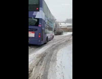 Purple bus slides down hill snow street