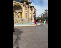 Woman red dress sways front of fountain