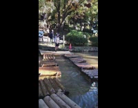 Three guys run across floating wood platforms different weights