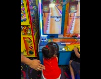 Little girl plays driving game at arcade 