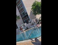 Lady in brown bikini poses with wind at pool 