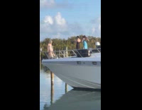 Woman beach dress poses front of boat