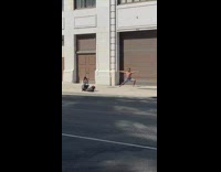 Man in shorts in a yoga pose on the sidewalk