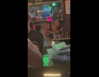 Woman stands to twerk near her friends in the bar