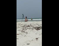 Girl black cap bikini sit tripod beach