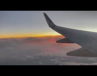 Guy sees colorful sky out airplane window 