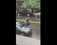 Man cleans his car in the rain 