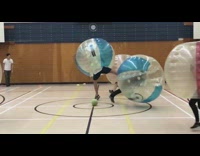 People in bumper ball bump each other gym