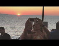 two older women taking picture of sunset by beach
