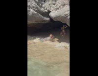 Woman bikini under cave waves hit photographer