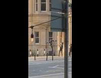Man jacket stands on garbage bin holds on pole