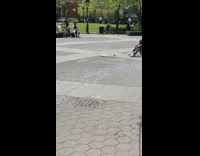 Person Lays on Ground for Photo While Cardboard Smokes 