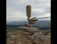 Guy stacks flat rocks on mountain 