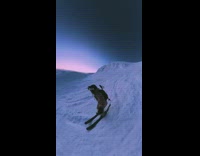 Brown jacket girl skis down mountain sunset