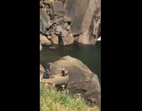 White hat girl sits flat rock waterfall 