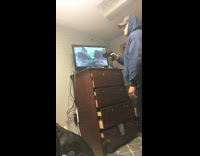 Guy blue sweatshirt pulls trigger on stun gun and points at friend on bed, friend screams