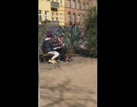 Guy play guitar sing bob marley song park bench