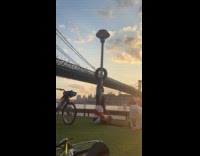 Collab WINY - Man climb pole and balances tire on head park near bridge