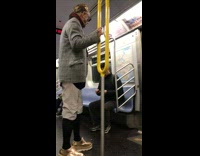 Man in coat has black plant smeared on face on subway train