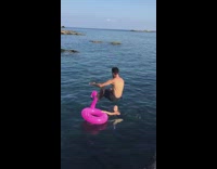 Guy front flip fail off rocks into pink flamingo floatie water