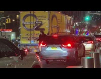 Woman hitching a ride on the back of a moving van