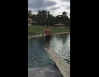 Man cannonballs off diving board and dives head first into swimming pool slow motion