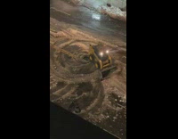 Yellow snowplow does donuts in empty street