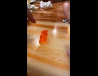 Person flicks orange jiggly jello on table