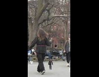 Woman walks in the park and holds a voodoo puppet doll of herself attached to strings