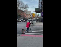 Woman in red vest vacuuming the crosswalk with a power vacuum 
