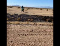 Person on green motorbike flies over bump 