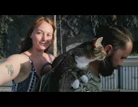 Pet cat strapped on drivers back for a scooter ride