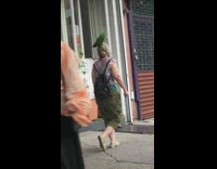 Lady green bird head black backpack sidewalk 