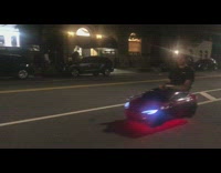 Guy rides kids toy red car down the street at night