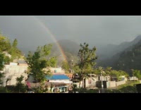 Full rainbow on mountain over houses rain