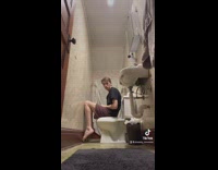 Guy sitting in tight bathroom legs on wall