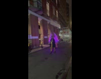 Two ladies wear matching purple christmas trees outside 