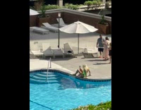 Blonde woman green swimsuit sit on poolside