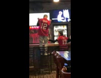 Guy stands on bar stool and celebrates 