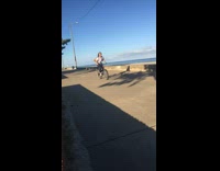 Red bicycle wheelie fail beach white shirt 